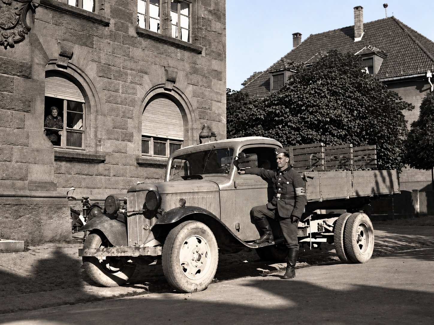Historische Aufnahme eines Fahrers neben einem frühen Pritschen-Lastwagen vor einem Gebäude