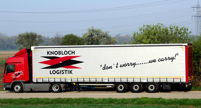 Weißer Knobloch Logistik LKW mit rot-schwarzem Logo auf der Plane vor der Verladehalle